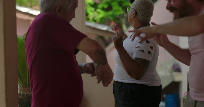 Elderly man, a cheerful Black woman, and younger man dancing together in a lively outdoor gathering, showcasing diversity, joy, and community bonding