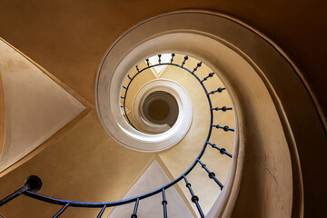 A captivating view of a spiral staircase, photographed from the bottom looking up to the top. The intricate design and elegant curves create a mesmerizing and dynamic visual effect.