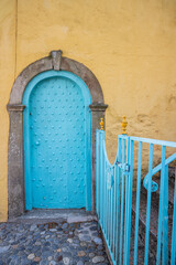 An aqua colored door on a yellow stucco building.