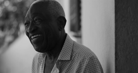 African American elderly man laughing joyfully while leaning against a wall, captured in black and white, exuding happiness, contentment, and emotional warmth