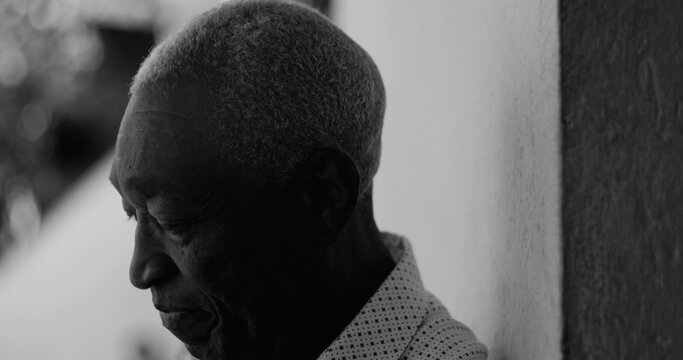 African American elderly man laughing while leaning against a wall, captured in black and white, conveying joy, positivity, and emotional depth