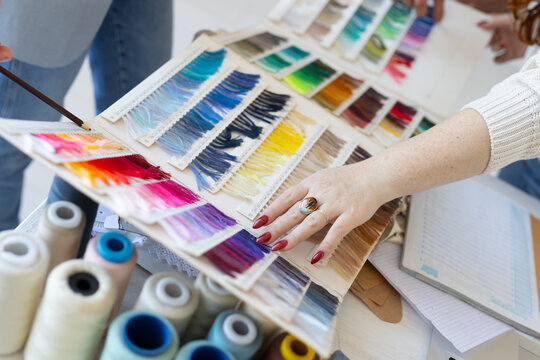 Hands choosing textile color shades in creative workspace. Collaboration, aesthetic decision, and teamwork in modern fashion design.