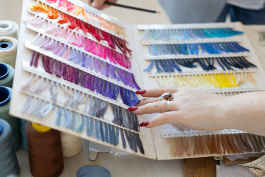 Fashion designer arranging fabric color swatches and samples in studio. Inspiration, design development, and textile craftsmanship.