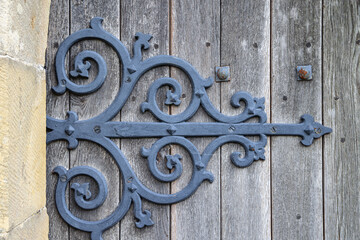 Ornate antique iron hinge on the door of a historic church in Wales.