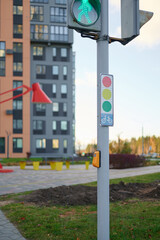 urban traffic light showing green pedestrian symbol near modern residential complex with colorful facades, symbolizing safe city infrastructure and contemporary urban living focus