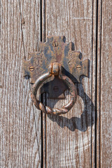 Rusted iron door pull ring on a weathered wooden door.