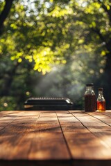 A rustic wooden table with a grill and bottles of barbecue sauce set against the backdrop of a beautiful day.