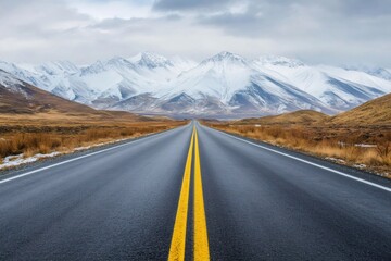 Naklejka premium Long paved highway leading to snow capped mountains