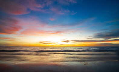 Fototapeta premium serene panorama image capture beauty sunset over calm ocean. sun low on horizon casting warm golden glow across sky and reflect off gentle wave. warm orange near creating peaceful calm atmosphere.