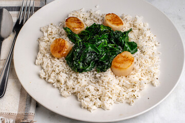 rice top with spinach and scallops