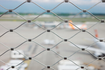 Metal security mesh fence with blurred airport runway background