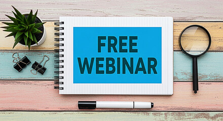 Free webinar advertisement on a notepad with a plant and magnifying glass on a colorful wooden desk promoting online learning opportunities