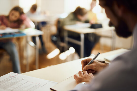 Close up of unrecognisable male teacher writing his plans in the classroom. - Powered by Adobe