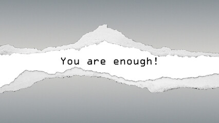 Inspirational quote “You are enough!” on torn paper texture with grey background. A positive message of self-worth and confidence.