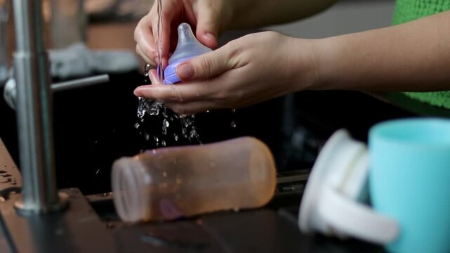 Close up of a woman cleaning a bottle and nipple for baby milk with a brush