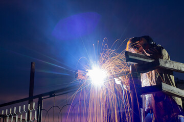 A welder welds a structure at night due to the urgency of the installation, a safety violation