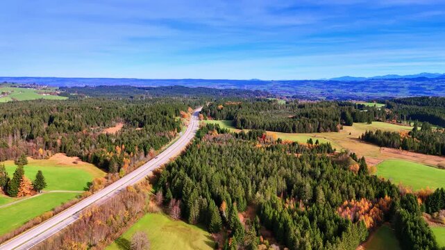 Modern wide highway crossing the natural landscape of meadows and woods. Aerial view on the sunny countryside of Weitnau, Bavaria, Germany.