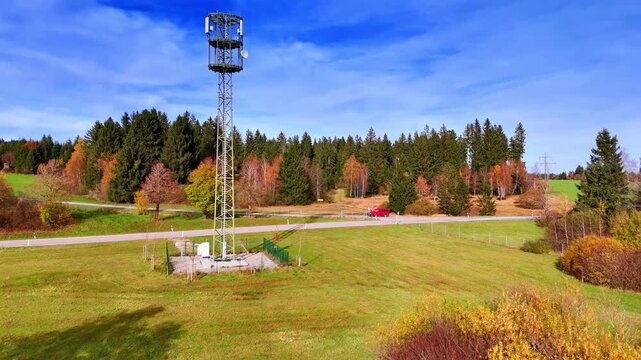 Going up near the radio tower standing in the meadow. Reveling aerial view on the wood and rural residential area in Weitnau, Bavaria, Germany.