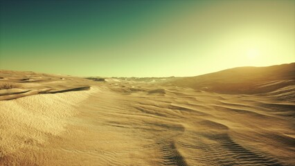 Golden rays of the sun illuminate the sandy dunes of a vast desert landscape. The scene captures the stillness and beauty of dawn as shadows dance across the sands.