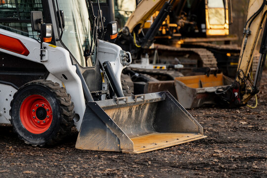 Detailed view of skid steer loader with dirt bucket attachment, symbolizing versatility and compact power of construction equipment used for landscaping, excavation and material transport operations