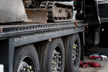 Flatbed truck loaded with excavator track section during equipment transport, representing industrial logistics, heavy machinery delivery, construction site supply chain and mechanical freight ops