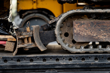 Close-up view of excavator steel track and undercarriage placed on transport trailer, representing heavy construction machinery, industrial logistics, mechanical equipment relocation