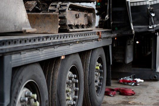 Truck trailer carrying excavator parts used in construction and earthmoving operations, illustrating industrial transport logistics, mechanical freight handling and heavy machinery relocation systems