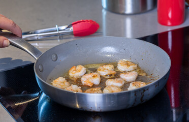 A close up of prawns cooking in butter in a frying pan.