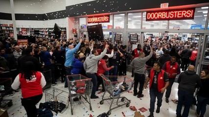 Frenzied mob of consumers storms an electronics store for doorbuster deals. Chaotic scene of consumerism during a major holiday sales event. Wide shot with slight panning and tilting.