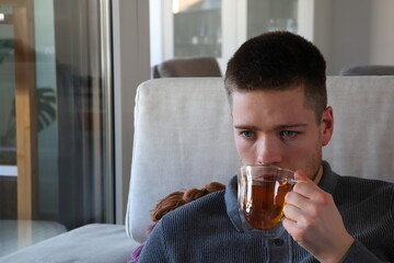 man drinking cup of tea on couch