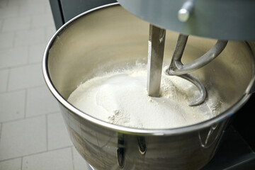 Mixing bowl filled with flour and dough hook in a professional kitchen, showcasing baking preparation and culinary artistry in action