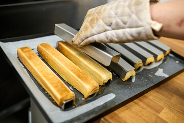 Baking process of golden brown pastries being removed from tray with oven mitt, showcasing delicious treats and kitchen environment