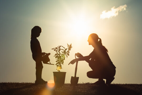 Mother and Child Planting a Tree Together at Sunset – Environmental Sustainability and Family Bonding - Powered by Adobe