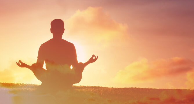 Silhouette of a man meditating outdoors at sunset, symbolizing peace, mindfulness, relaxation, and spiritual wellness in nature.