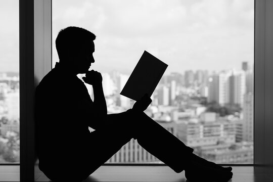 Silhouette of Man Reading Book Reviewing Paperwork – Stress, Problem Solving, and Planning