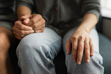 Close-up of a couple holding hands while sitting together, showing love, comfort, and emotional support.