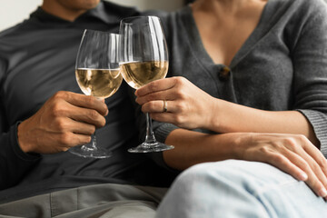 Close-up of a couple clinking wine glasses while relaxing together at home.