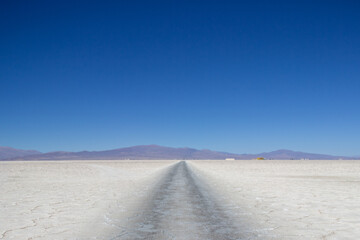 Camino atravesando las Salinas Grandes bajo cielo azul, Jujuy, Argentina