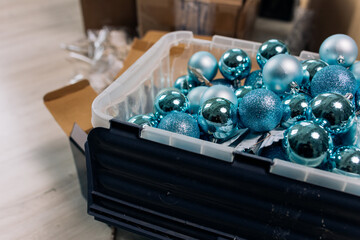 Preparing for the Christmas celebration: cardboard boxes with blue Christmas balls from the delivery service are placed in the living room of a residential building. The room is in disarray and chaos