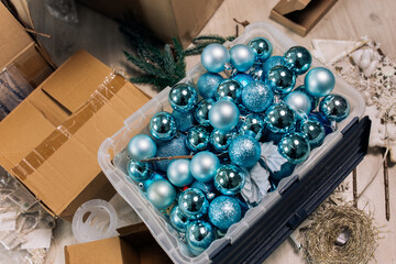 Preparing for the Christmas celebration: cardboard boxes with blue Christmas balls from the delivery service are placed in the living room of a residential building. The room is in disarray and chaos