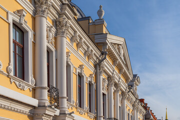 Facade fragment of an old mansion in an eclectic style with rich stucco moldings and columns. An elegant architectural background for the concept of luxury, culture, and history.