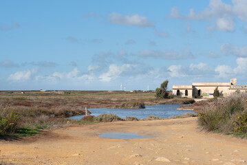 View of the Capo Feto nature reserve near Mazara del Vallo, Sicily. It has been raining and the paths and many areas are flooded with water. In the background is an old concrete house.