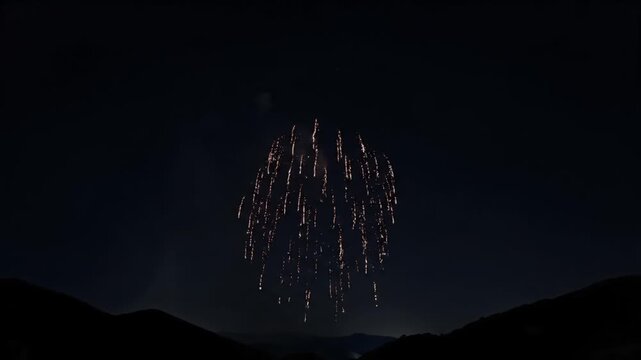 Spectacular Golden Firework Display Exploding in the Dark Night Sky Above Silhouetted Mountains for Festive Celebrations and Dazzling Evening Events