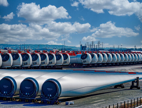 Rows of wind turbine components line the dock at sunrise