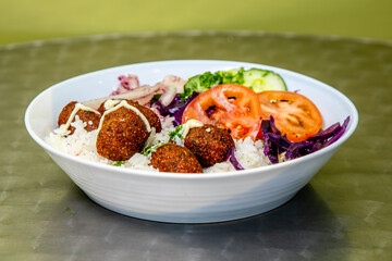 A middle Eastern felafel salad with felafel, tomato, cabbage on a bed of rice