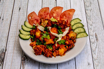 Traditional Indian dish. Aloo Gobi, cauliflower and potatoes on a plate with tomatoes, coriander, cabbage and cucumber