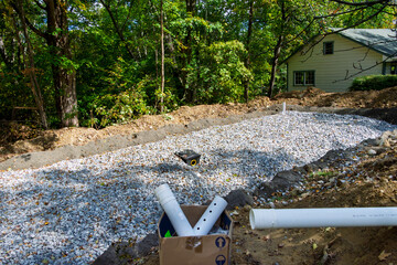 Home septic system leach field in progress with crushed stone layer, and the distribution box waiting for the input pipe
