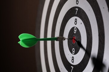 Dartboard with dart on black background, closeup