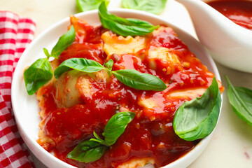 Delicious ravioli with tomato sauce and basil on white table, closeup