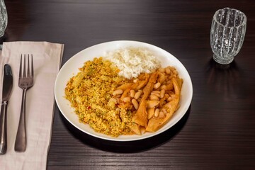 A classic Brazilian dish known as dobradinha, prepared with beef tripe, white beans, and tropical spices, served with traditional farofa made with toasted cassava flour.
